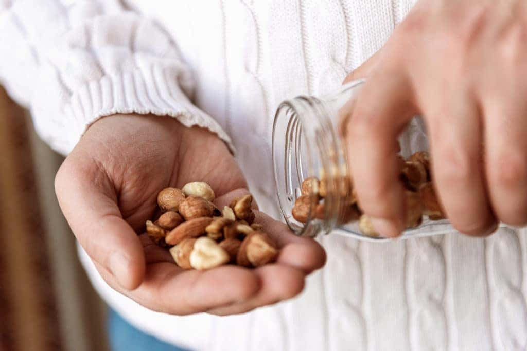 Man holding a jar of walnuts hazelnuts and almonds