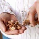 Man holding a jar of walnuts hazelnuts and almonds