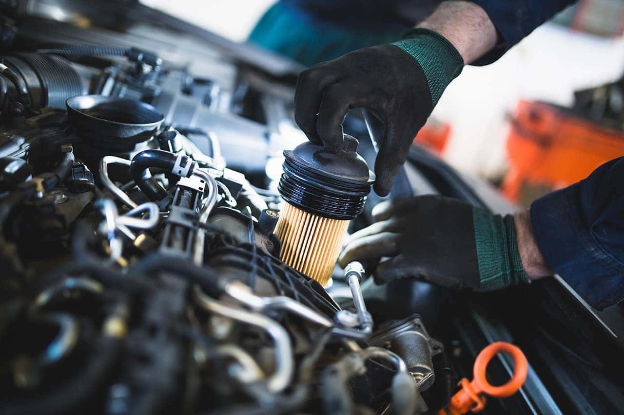 Technician changing an oil filter to improve Mazda fuel efficiency