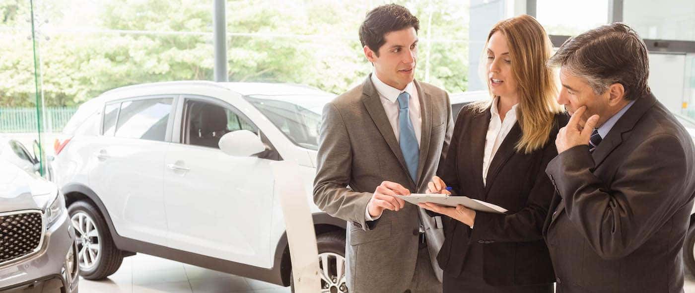 Sales team look at a clipboard at new car showroom
