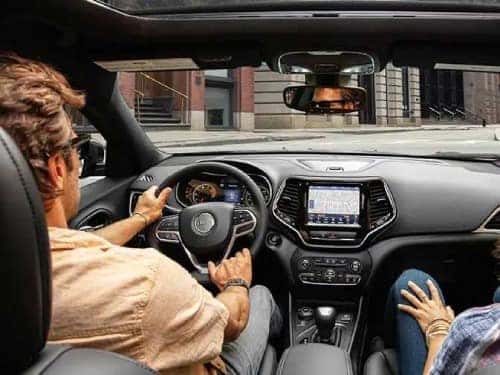 2024 Jeep Wrangler 4xe interior view of couple in front seat driving down the road