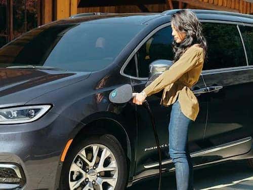 2024 Chrysler Pacifica PHEV view of woman charging vehicle