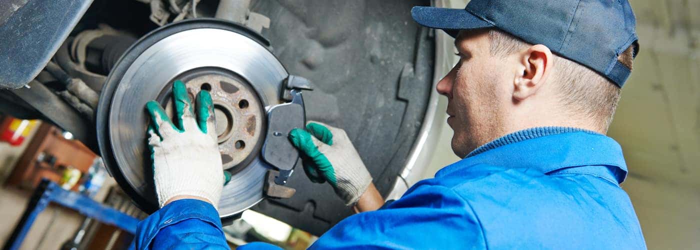 close up of mechanic repairing suspension and brakes