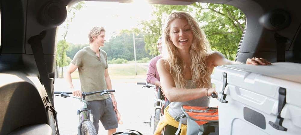 happy-woman-unloading-cooler-from-trunk