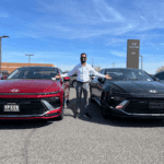 A car salesman showing off 2 Hyundai Sedans on the lot