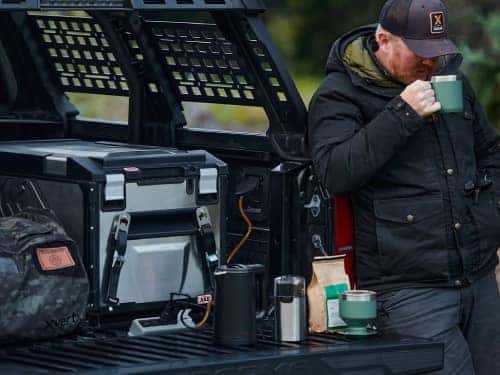 2024 Toyota Tacoma view of bed full of camping supplies and man using 2400w power inverter
