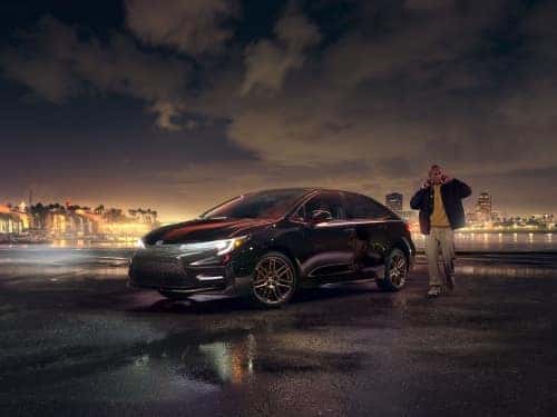 2024 Toyota Corolla Hybrid parked on a blacktop outside a city at night