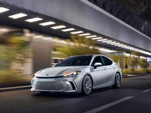 2025 Toyota Camry side exterior view of car driving at night on a road