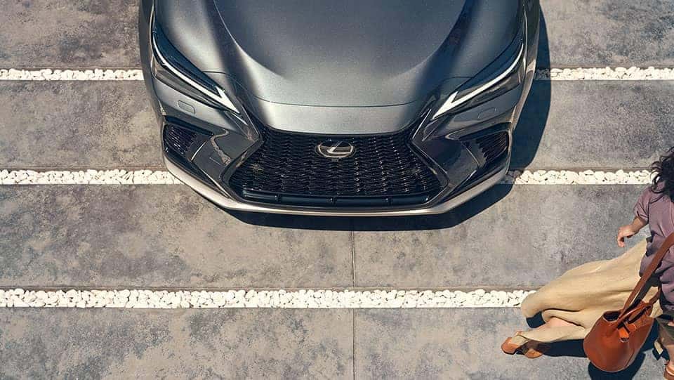 Woman walking in front of hood of silver Lexus